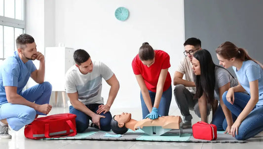Emergency First Aid and CPR online course showing CPR practice on a training manikin in a Canadian first aid class.
