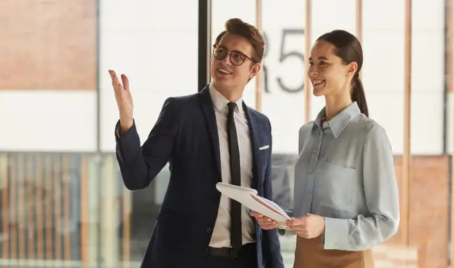 Commercial manager presenting office space to a client while reviewing business documents in a modern workplace