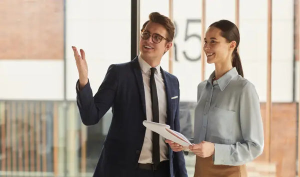 Commercial manager presenting office space to a client while reviewing business documents in a modern workplace