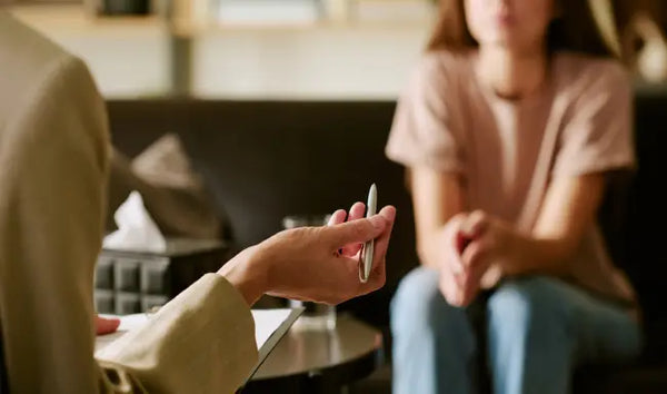 Psychological wellbeing practitioner providing mental health counseling and emotional support during a one-on-one therapy session.